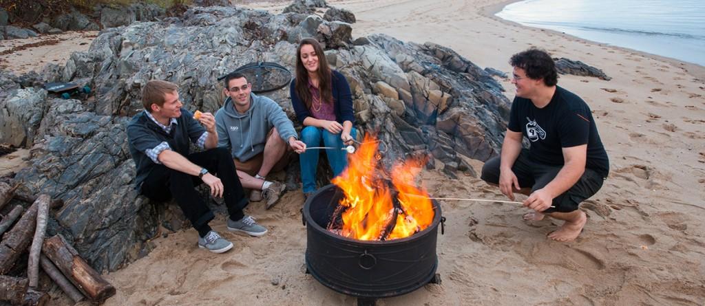 一群学生围坐在海滩上的篝火旁