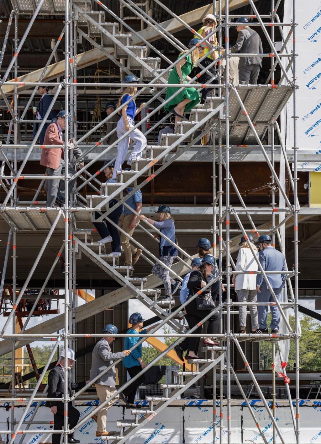 一群戴着施工帽的人爬上正在施工的建筑物的楼梯